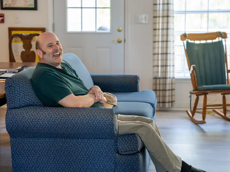 Resident smiling on couch in living room.