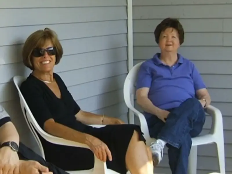 Resident and Employee sitting on front porch of a cottage talking