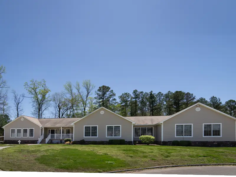 Anne Carter Robins Cottage exterior with walkway, landscaping, green grass and background of native trees