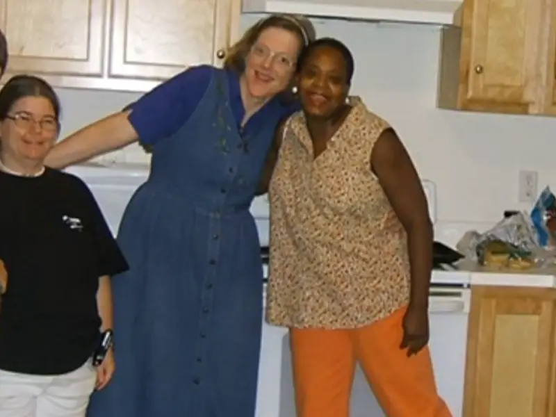 Residents and staff member in the kitchen smiling together