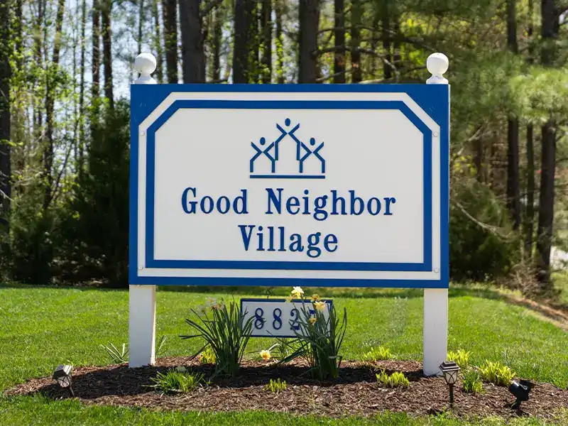 Good Neighbor Village exterior wooden sign with address and logo