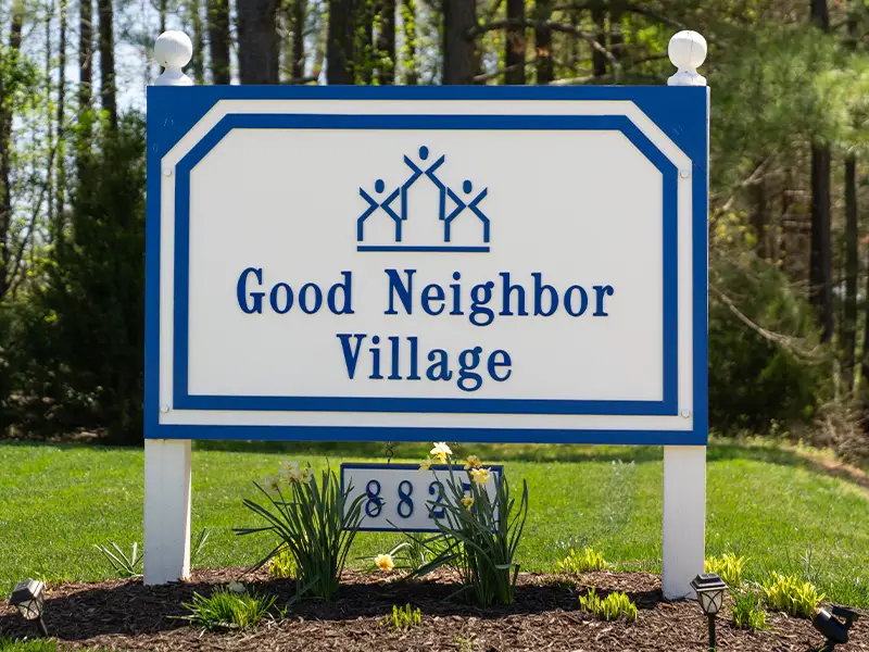 Good Neighbor Village blue and white sign with logo